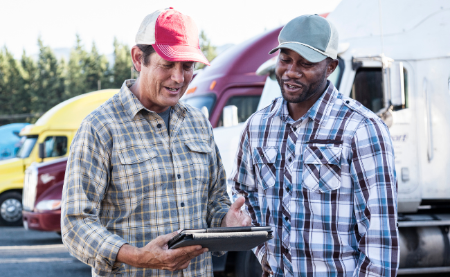 Two truck drivers reviewing Excelerate results using a tablet.