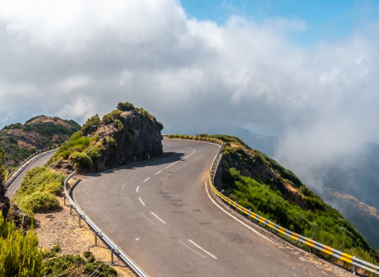 Curved mountain road with clear blue skies, demonstrating the challenge and precision needed in safe driving.