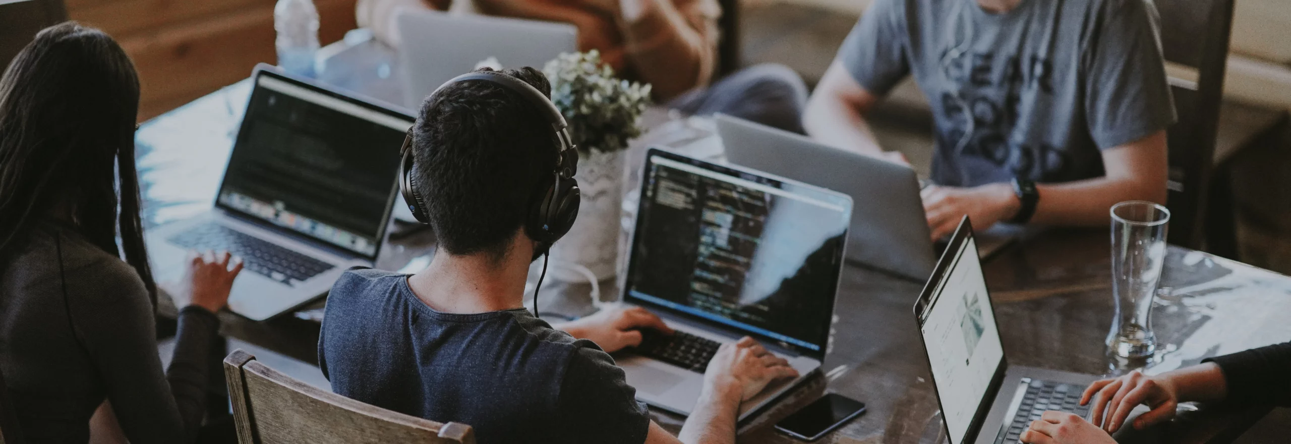 Group of people working on laptops in a collaborative workspace, representing teamwork and focus, used as a banner for case studies and use cases.