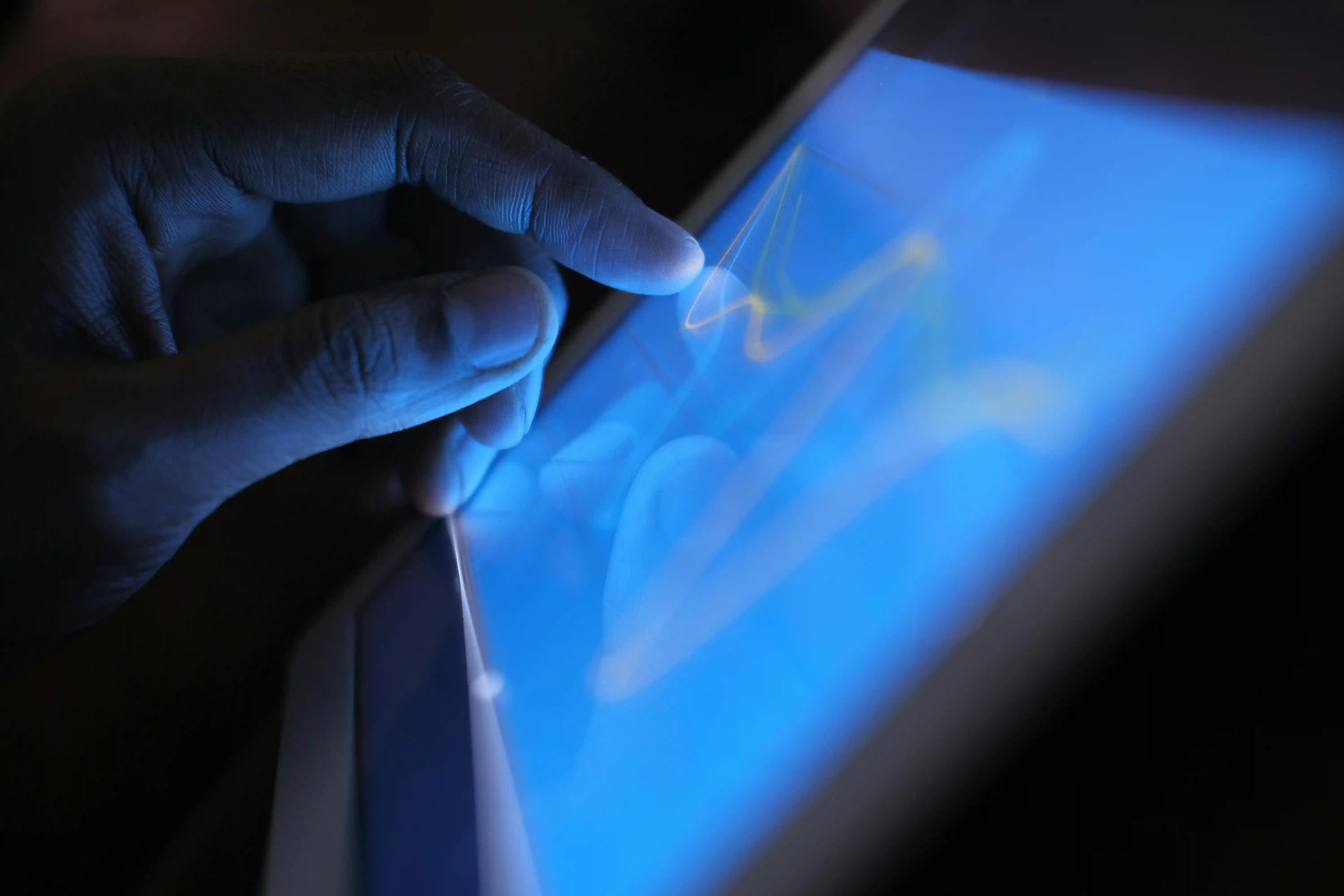 Close-up of a hand interacting with a tablet displaying a graph.