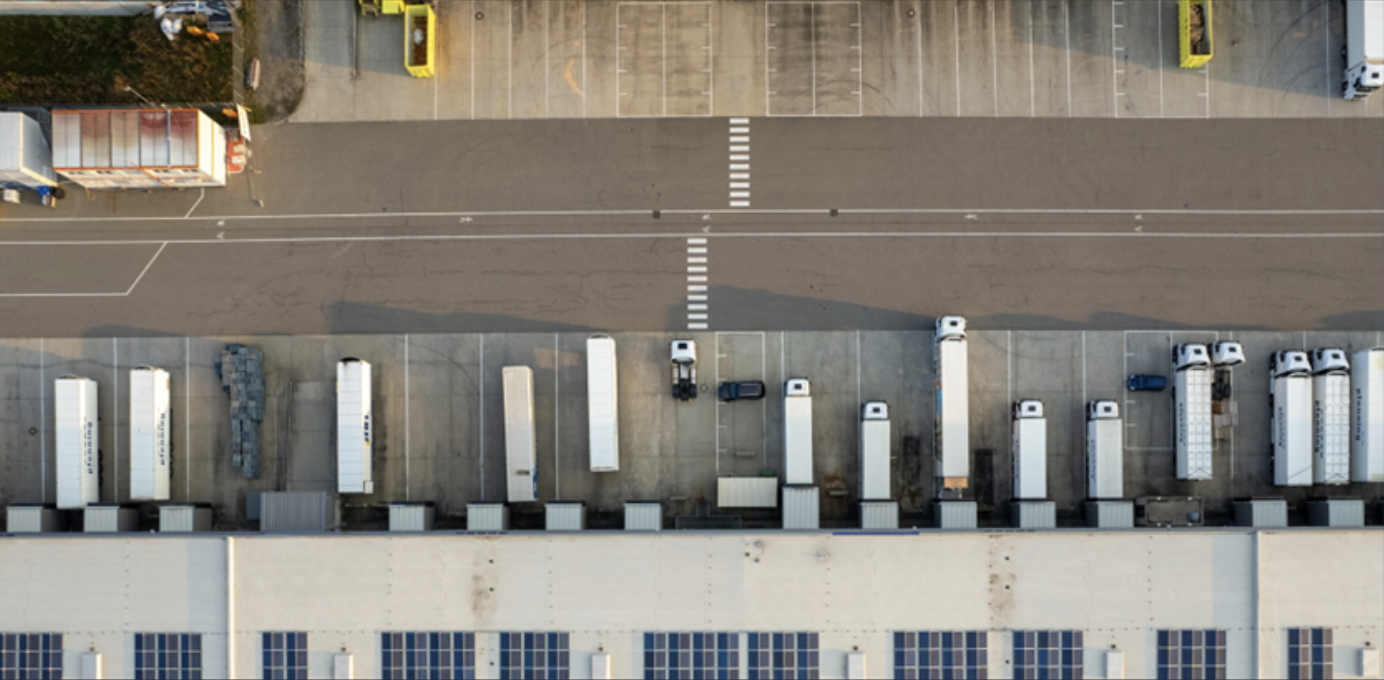 An aerial view of a truck fleet in a logistics hub. Neurapulse helps fleet managers monitor cognitive fitness for safe transportation.